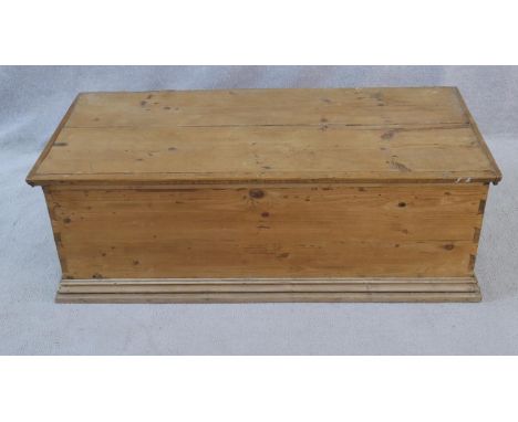 A 19th century pine lidded trunk with twin iron carrying handles on plinth base. H.38 W.109 D.49.5cm 