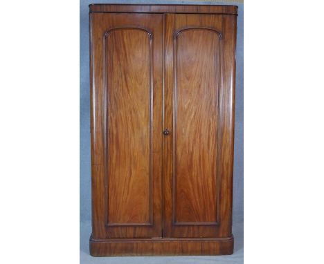 A 19th century mahogany wardrobe with arched panel doors enclosing hanging space (one side converted) on a plinth base. H.202