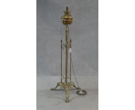 A Victorian brass standard oil lamp on reeded central column and tripod foliate swept supports, converted to electricity. H.1
