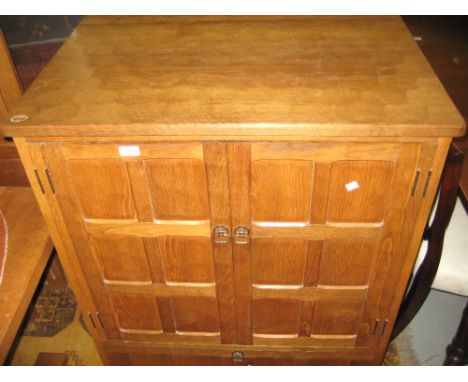 Alan (Acornman) Grainger, an oak side cabinet with a pair of panelled doors above a shallow fall front raised on bracket feet