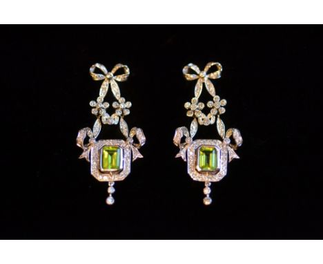 Pair of ornate Edwardian style 18ct white gold peridot and diamond drop earrings, each with a bow surmount above a floral gar