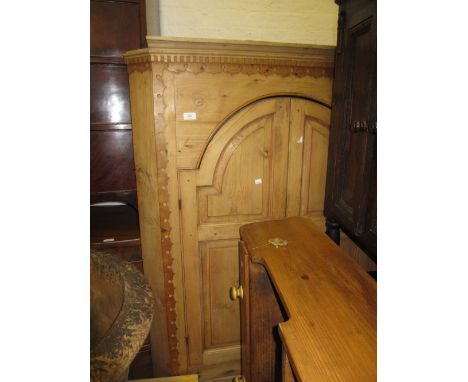 19th Century polished pine standing corner cabinet with a moulded cornice above two arched doors enclosing shaped shelves, ab