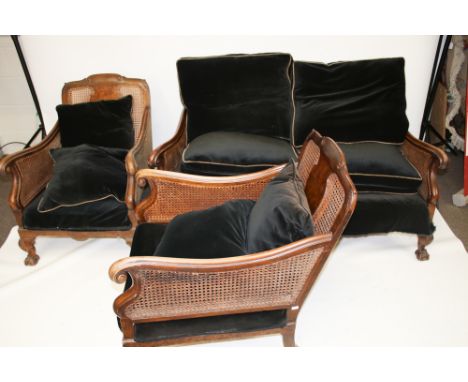 A 20th century bergere suite. Comprising a two seat sofa and two chairs, all with carved mahogany and burr walnut frames, rai