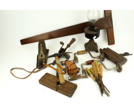 A collection of assorted vintage hand tools. Including drills, planes, chisels, an oil lamp, etc.
