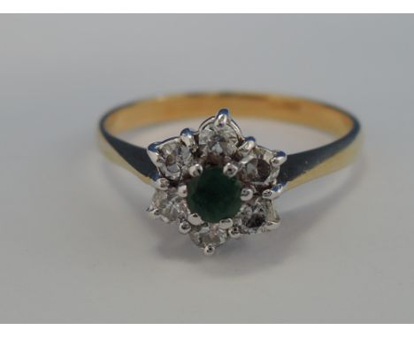 A ladies dress ring having an emerald and diamond cluster on a yellow metal loop stamped 18ct