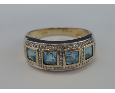 A ladies band ring having four square cut blue topaz with diamond chips within a false setting on a 9ct gold loop