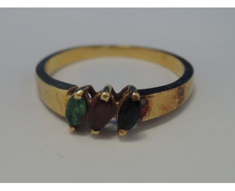 A ladies dress ring having a lozenge shaped emerald, ruby and sapphire on a yellow metal loop stamped 750