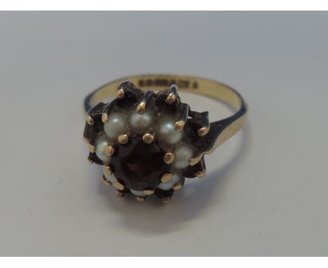 A ladies dress ring having a garnet and seed pearl double cluster on a 9ct gold loop