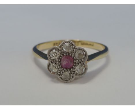 A ladies dress ring having a ruby and diamond daisy cluster on a yellow metal loop stamped 18ct & plat
