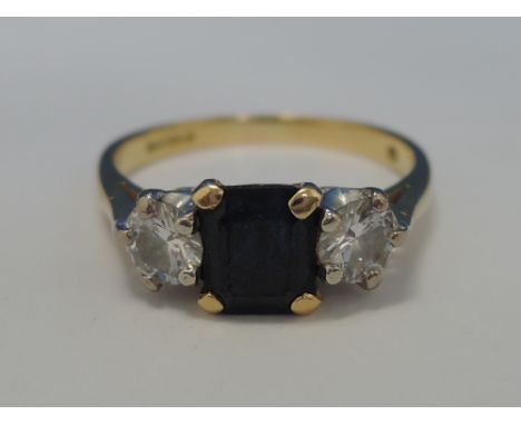 A ladies dress ring having a rectangular blue sapphire flanked by two diamonds each approx .25ct in a raised claw setting on 