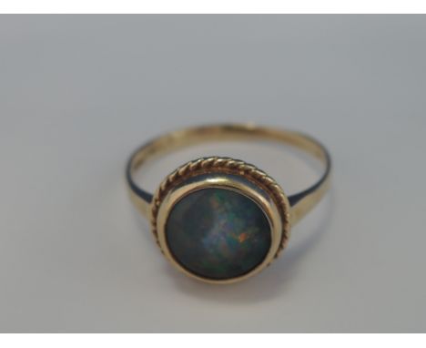 A ladies dress ring having a black opal  triplet stone in a collared mount with rope twist decoration  on a 9ct gold loop