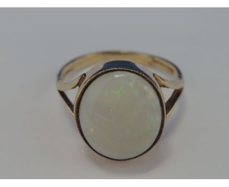 A ladies dress ring having an oval opal in a raised band mount with open shoulders on a 9ct gold loop