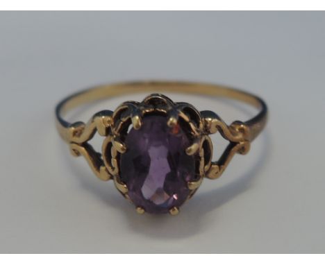 A ladies dress ring having an amethyst style stone in a decorative mount on a yellow metal loop, no marks possibly 8ct