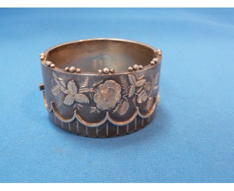 A Victorian silver hinged cuff bangle having raised scallop and floral decoration, Birmingham 1884, Constantine & Floyd