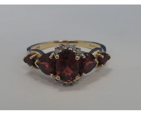 A ladies dress ring having a central garnet with diamond chip decoration and flanked by two heart shaped garnets to each shou