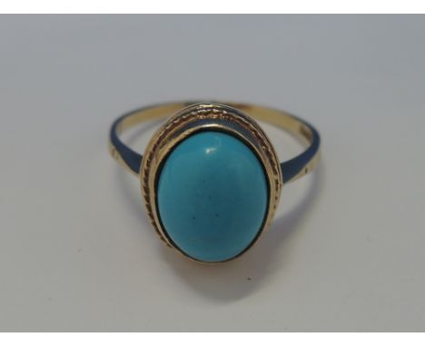 A ladies dress ring having an oval turquoise  in a collared mount on a 9ct gold loop