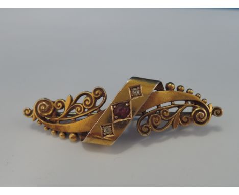 An Edwardian 14ct gold bar brooch having central band with ruby and two diamonds with scroll and bead decoration to each side
