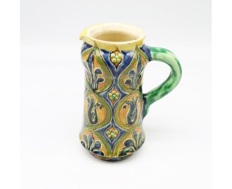 Della Robbia - a late 19th century art pottery jug, having stylised incised floral designs, in blue and greens, green glazed 