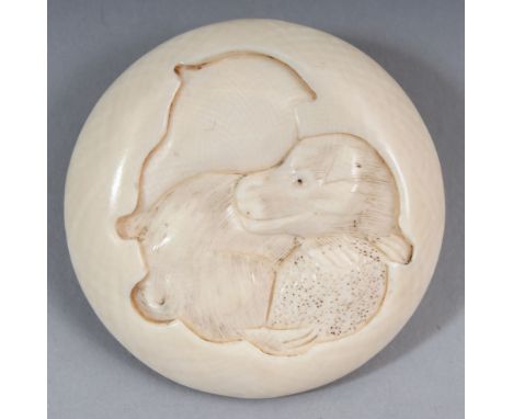 A SIGNED JAPANESE MEIJI PERIOD IVORY MANJU NETSUKE, carved to one surface with a seated puppy beneath a plain bird motif, the