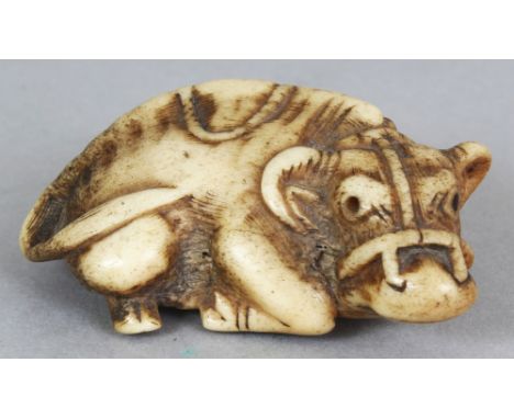 A JAPANESE MEIJI PERIOD STAGHORN NETSUKE OF A RECUMBENT OXEN, one of its eyes inlaid, 1.9in long.
