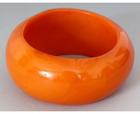 A LARGE AMBER-STYLE BANGLE, 3.8in diameter, the inner rim 2.7in diameter.