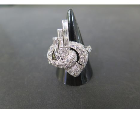 A Deco style diamond dress ring - The baguette and brilliant-cut diamonds to the plain band - Estimated total diamond weight 