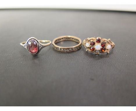 Three rings - To include a 9ct gold opal and garnet cluster ring, size P - A white-gem full circle ring, size L1/2 - Hallmark