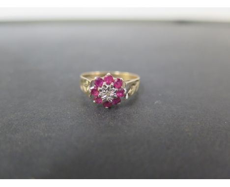 A 9ct gold ruby and diamond cluster ring - With foliate shoulders - Hallmarked London - Ring size O 1/2 - Weight approx 2.0gm