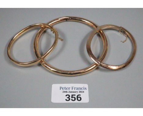 Two 9ct gold bangles.  23.5g approx., together with another yellow metal bangle.  10.5g approx.  (3)   (B.P. 21% + VAT) 