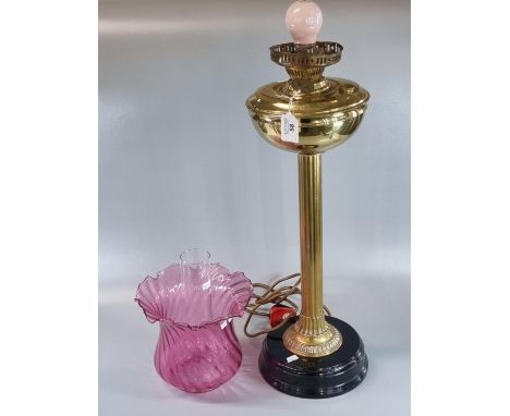 Early 20th Century oil burner lamp now converted to electricity, having cranberry glass shade, brass reservoir on an ebonised