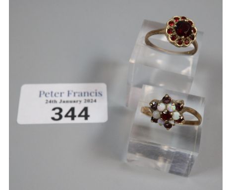 9ct gold garnet flowerhead ring.  2.8g approx.  Size O.  Together with 9ct gold opal and ruby or garnet flowerhead ring.  2.1