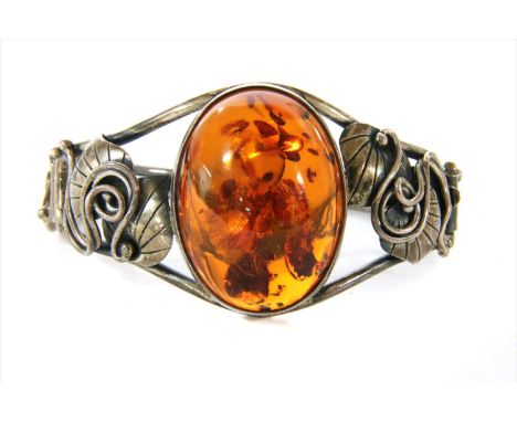 A sterling silver hinged amber bangle, with an oval cabochon amber, approximately 33 x 26 x 13mm, rub set to tapered wire gua