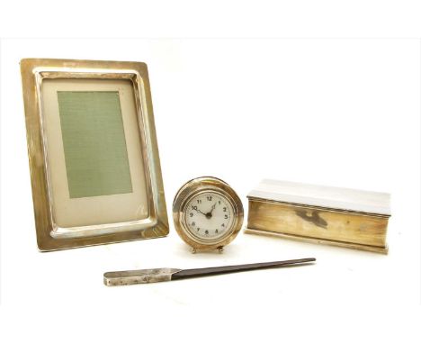 A silver cased travelling alarm clock, 9cm high, Birmingham 1926, together with a silver cigarette box, photograph frame and 