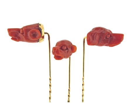 Three carved coral stick pins, realistically depicting dog's heads in coral, set in yellow gold