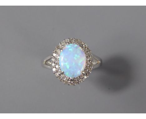 A 9ct White Gold Diamond and Opal Ring. The opal measuring approx 10 x 8 mm and surrounded by approx 30 pts of dias, size O, 