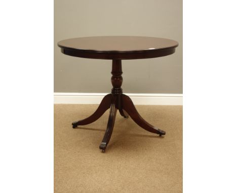Reproduction mahogany circular tilt top table, turned column with four out splayed legs, claw cups and castors, D91cm, H75cm
