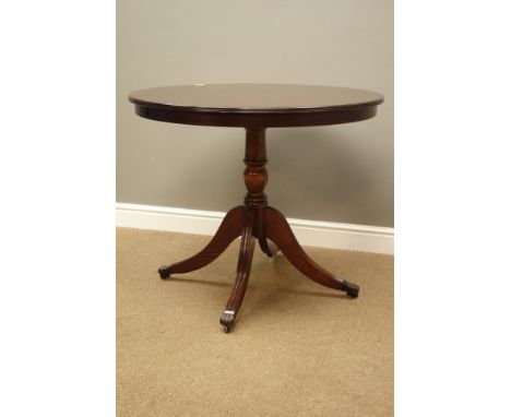 Reproduction mahogany circular tilt top table, turned column with four out splayed legs, claw cups and castors, D91cm, H75cm