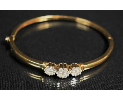 A 9ct gold and diamond hinge bangle, inset with thre clusters of seven round cut diamonds,  stamped 357, 12.2g gross