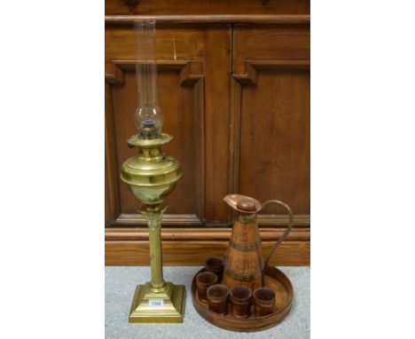 An oak coopered style jug and beakers on conforming tray; a brass oil lamp, reservoir supported on Corinthian column (2)