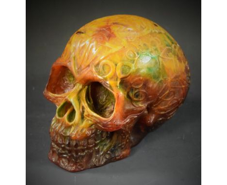 An amber coloured resin skull, cast with Celtic style scrolling decoration, 13cm high