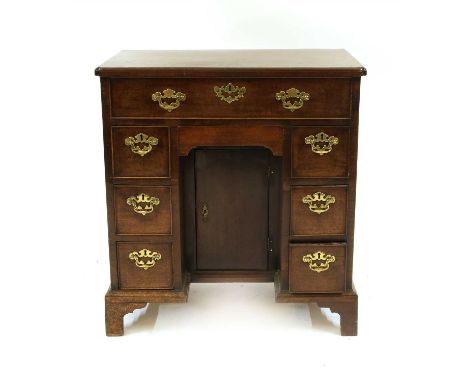 A mahogany kneehole desk, early 19th century, the top with re-entrant corners over eight drawers arranged around a cupboard b