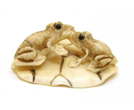 A small Japanese ivory netsuke, of two frogs in a water lily, signed, 3.8cm long