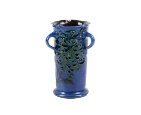 CH Brannam pottery cylinder three handle vase. Blue ground glaze with green floral design, marks to base. H14.5cm