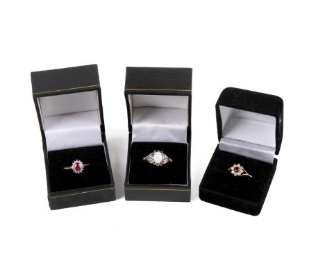 Three 9ct gold stone set rings. The flower set with eight small diamonds around a red stone, size O; diamonds around an oval 