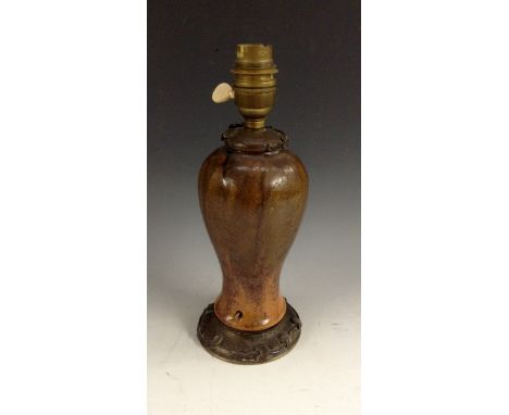 A French Art Nouveau inverted baluster lamp base, in mottled tones of brown and orange, hammered metal mounts with moulded tr