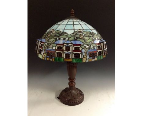 A modern stained glass table lamp, in the Art Nouveau style, lead casing with panes of glass depicting houses in relief again