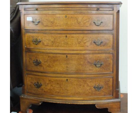 A reproduction Walnut and Mahogany bow fronted chest with brushing slide over four drawers on bracket feet