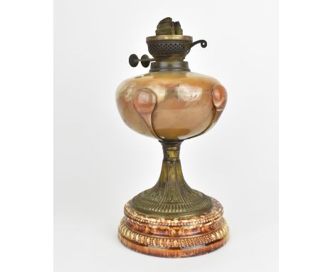 A 19th century Arts and Crafts style oil lamp, with bulbous glass body on a spreading metal pedestal above a circular mottled
