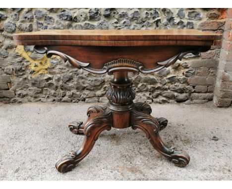 A William IV rosewood card table, the folding top revealing a red baize surface, above a thick moulded apron, supported on a 