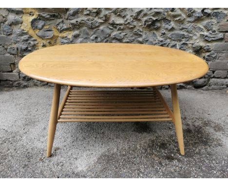 A light elm Ercol coffee table, of circular form with spindle magazine rack under tier, with label, 43 cm high x 98 cm wide x